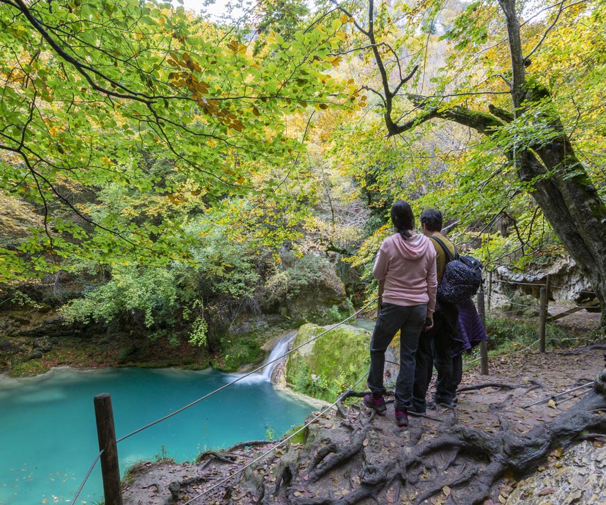 Pareja sentada observando las aguas turquesas del Urederra