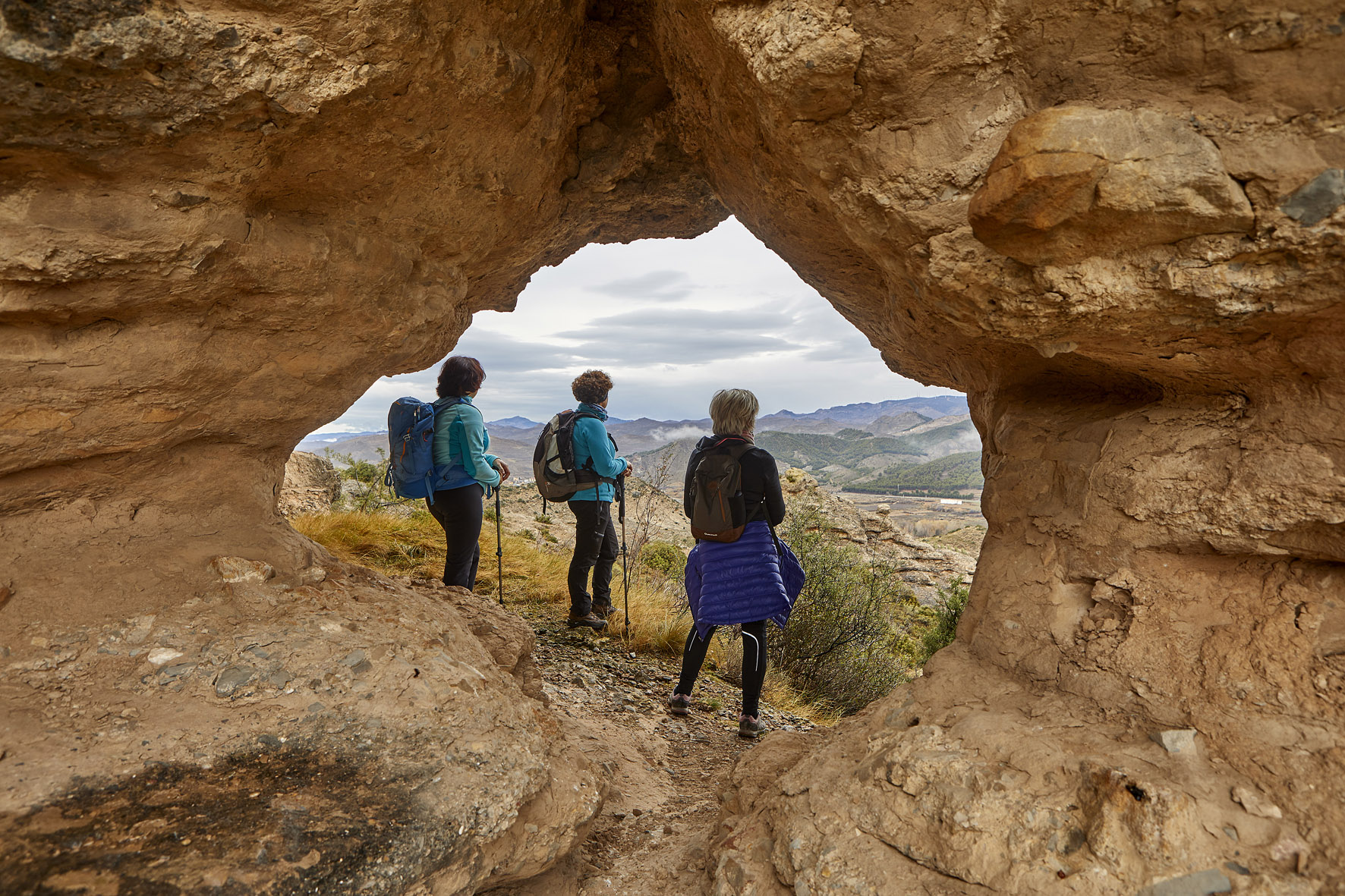 tres mujeres de pie en un agujero formado en las rocas