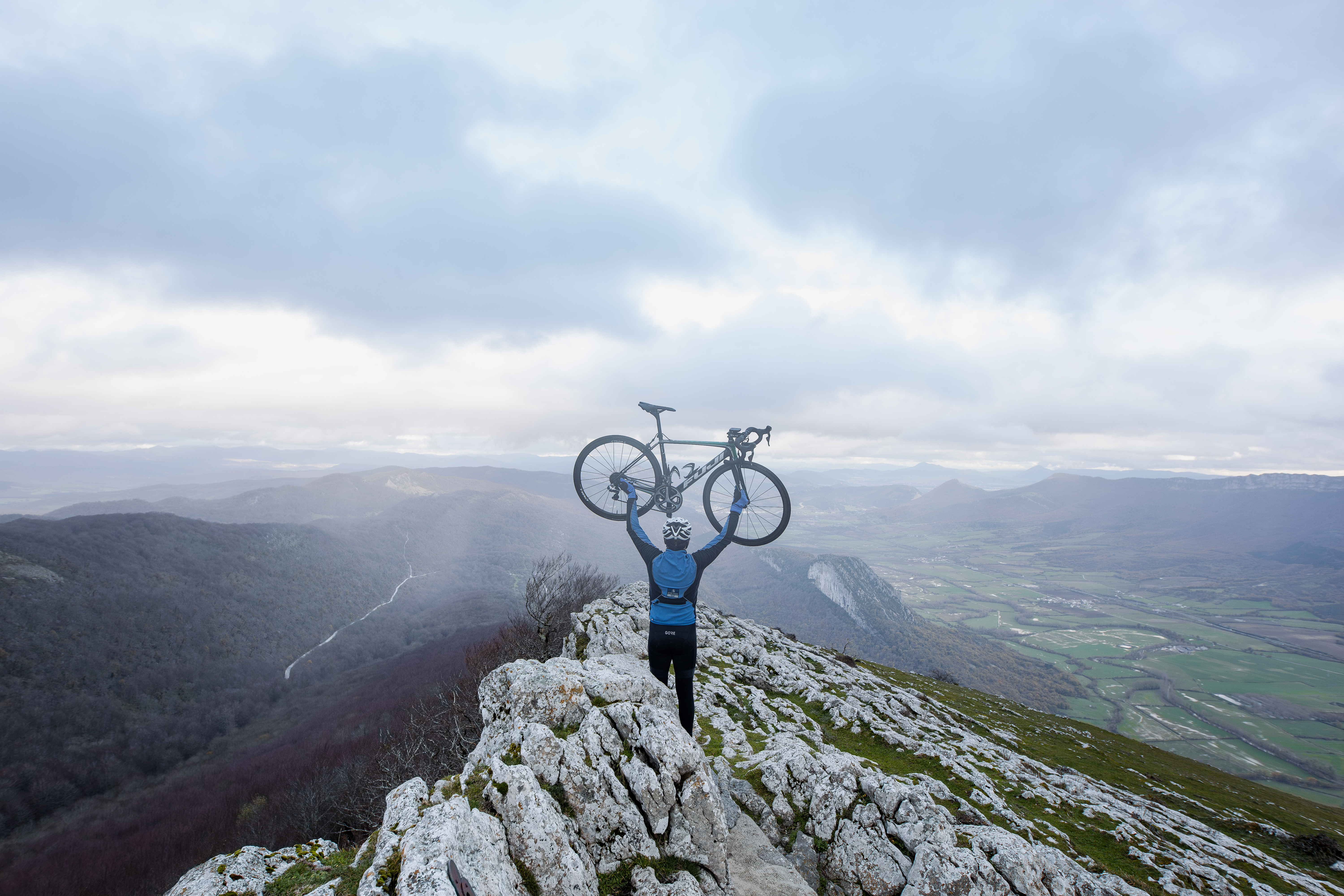Ciclista levantando la bici en la cima del monte