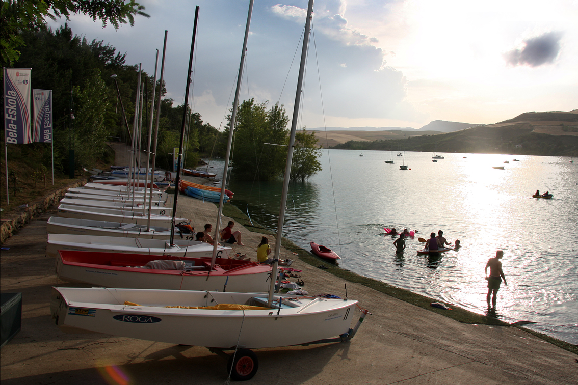 barcas en la orilla del embalse de Alloz y gente en el agua