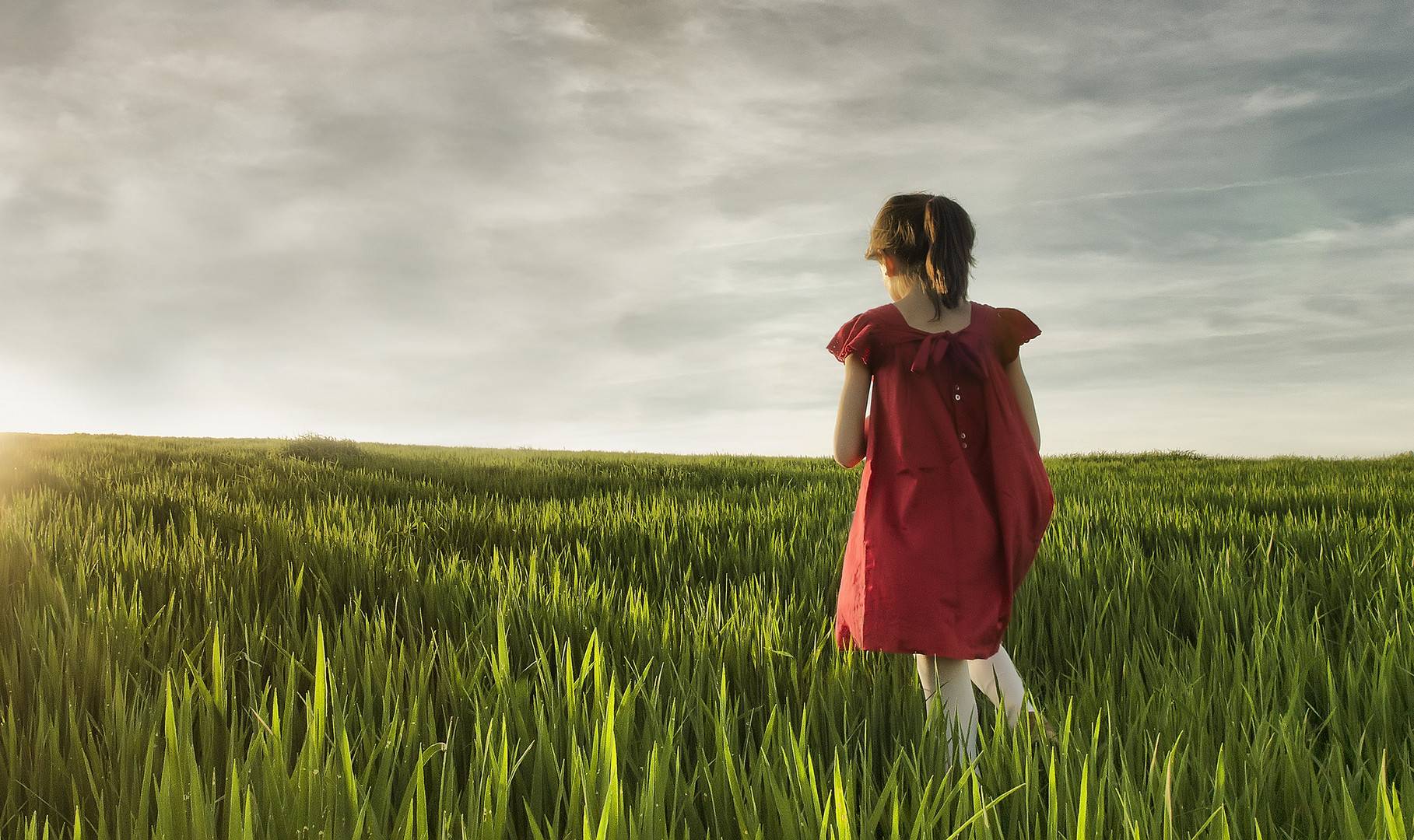 Girl in red dress in a green field