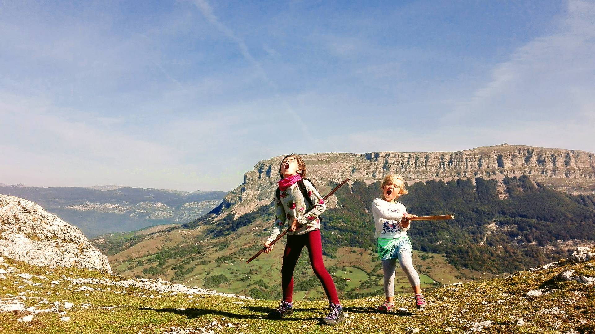 Dos niñas con palos gritando con el monte Beriain al fondo