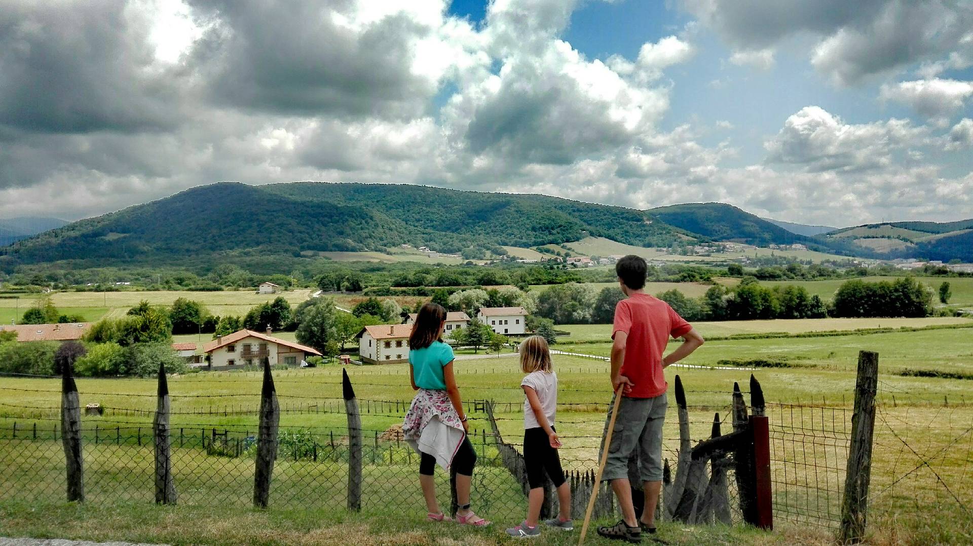 A father and his daughters contemplate a town in the Ultzama Valley