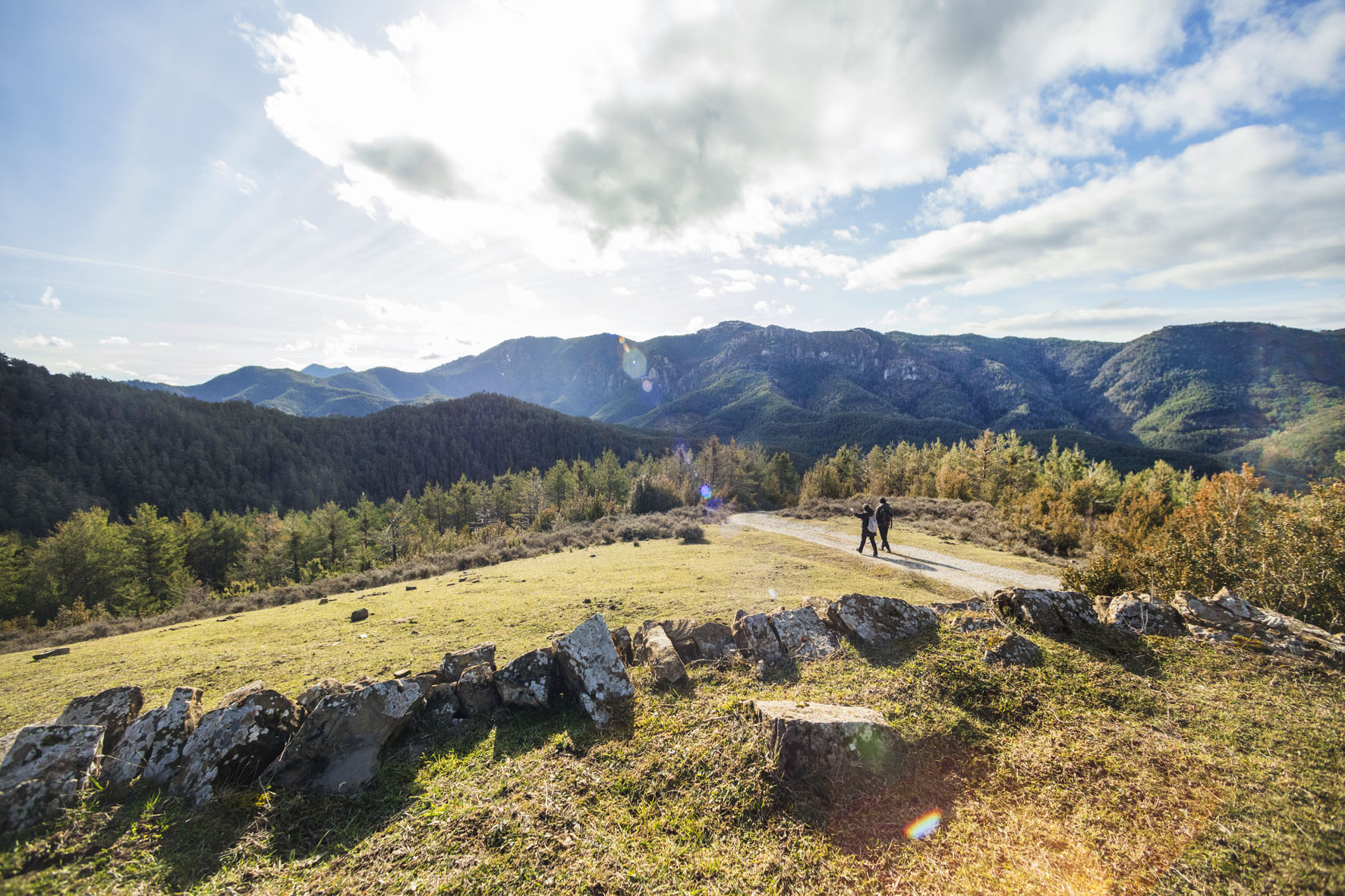 dos personas andando por un camino y al fondo se ven montes