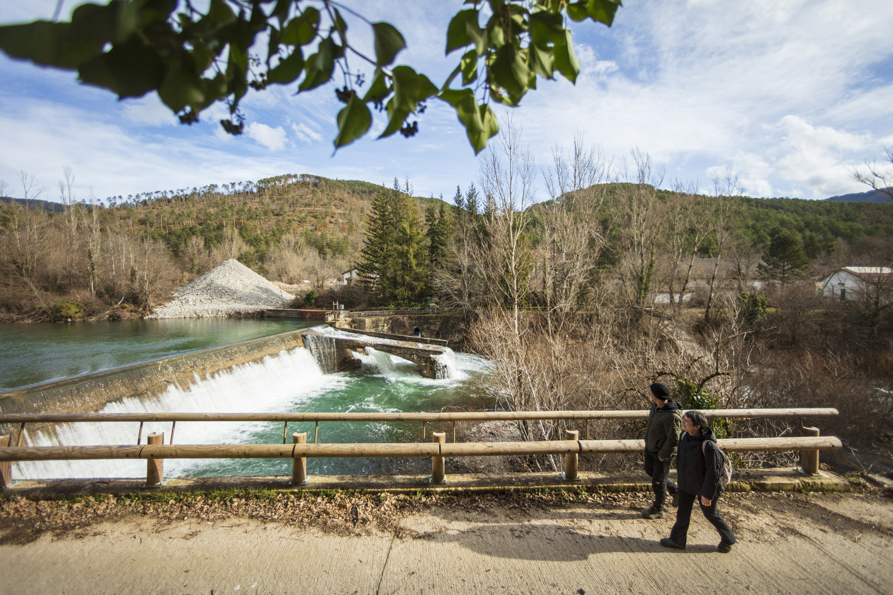 dos personas andando y por detrás se ve una presa en el río