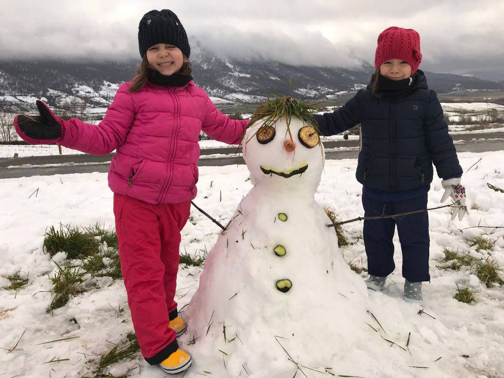 Two girls next to a snowman