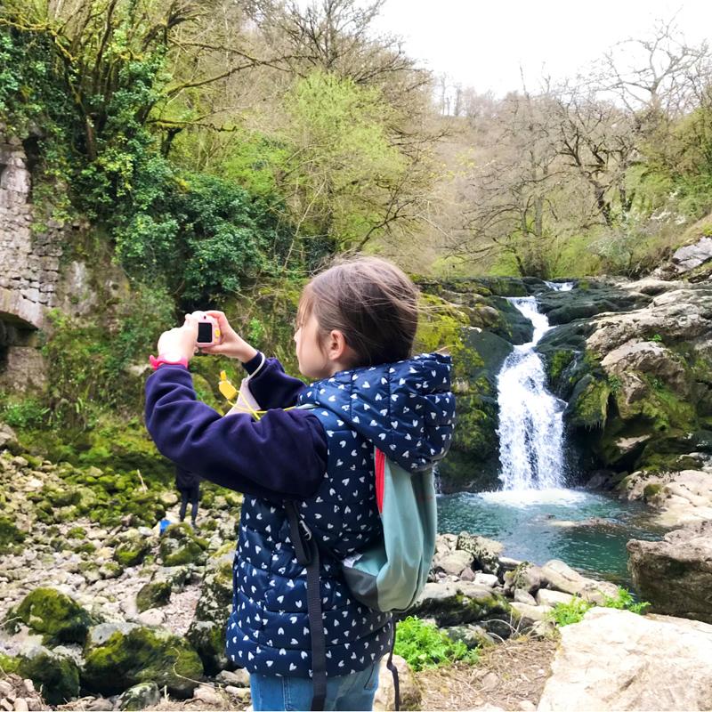 Niña haciéndose un selfie al lado de la cascada