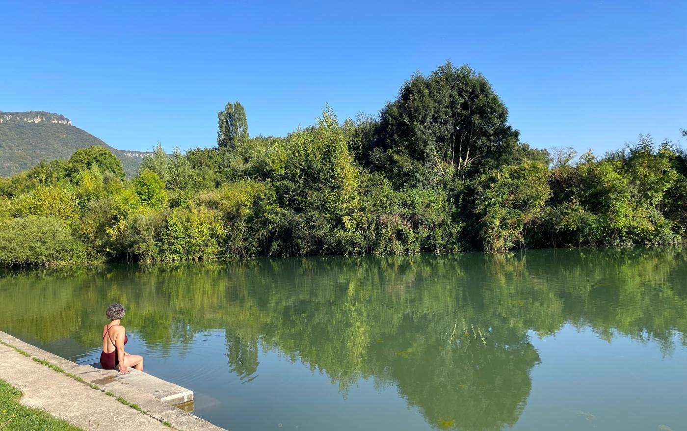 Mujer sentada en bañador al borde de un embalse