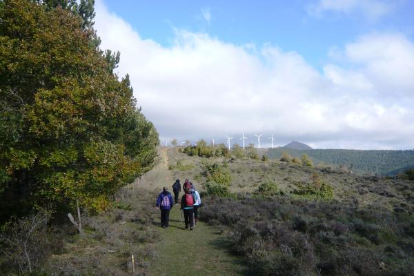 Personas andando por el monte y al fondo molinos