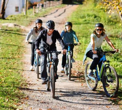 Familia andando en bicicleta por un camino y al fondo se ve un caserío