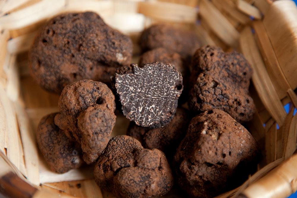 cesto de mimbre con trufas negras y una está cortada por la mitad