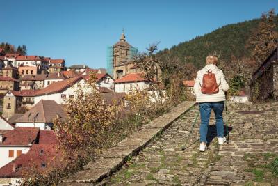 Una mujer de espalda con bastones andando po una calle de Uztárroz en Roncal