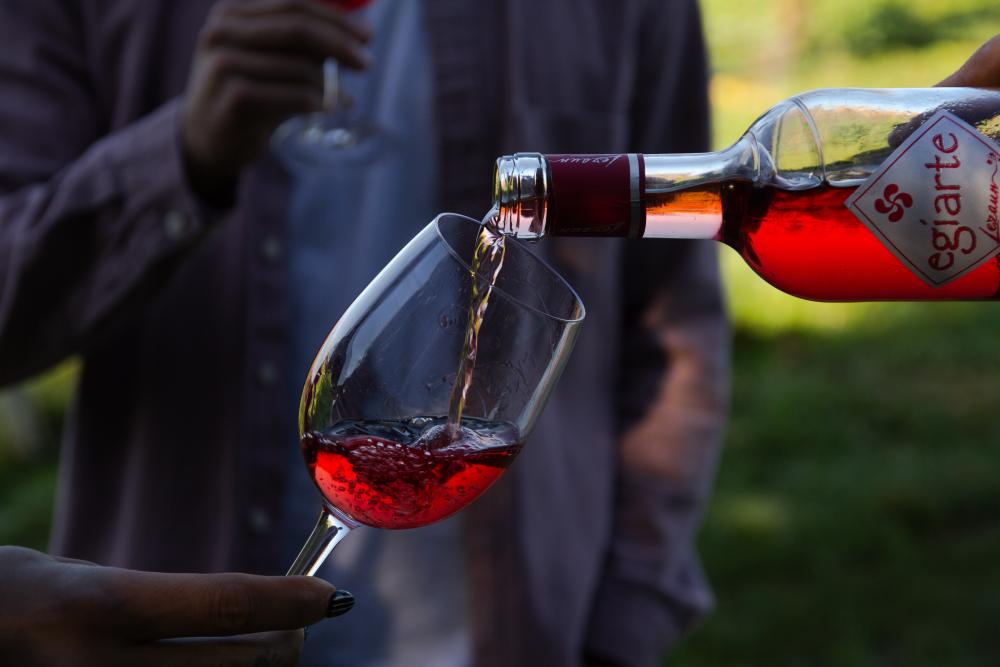 Sirviendo vino rosado de una botella a una copa