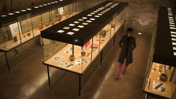 Chica recorriendo las vitrinas expositivas del Museo de Tudela con objetos de la antigüedad