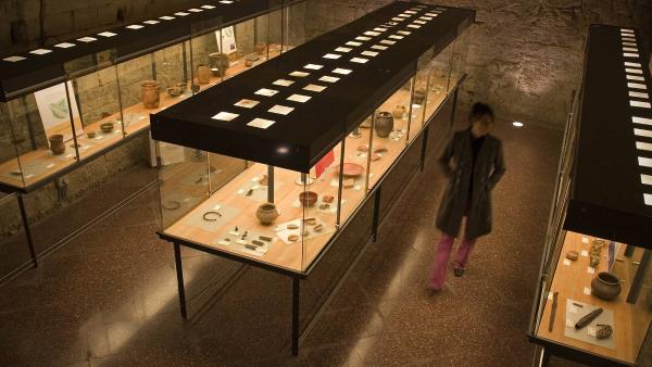 Girl visiting the exhibition windows of the Museum of Tudela with objects from antiquity