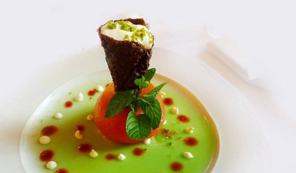 Haute cuisine dish from Navarra with bright colors consisting of a soup, confit tomato and a stuffed cornet