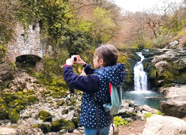 Niña sacando fotos junto a la cascada de Ixkier