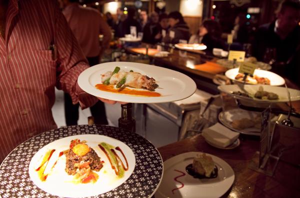 A waiter pulling out two plates of portions in a bar